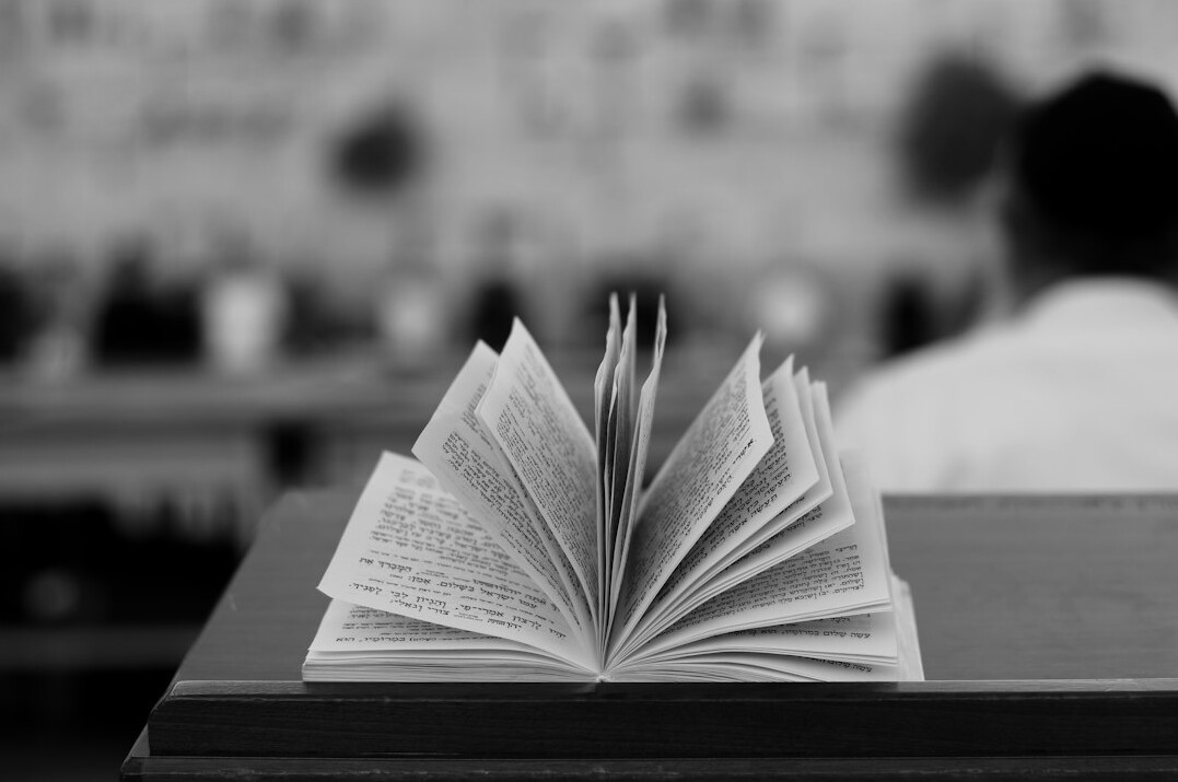 Open book and handwritten notes on a wooden desk in warm light